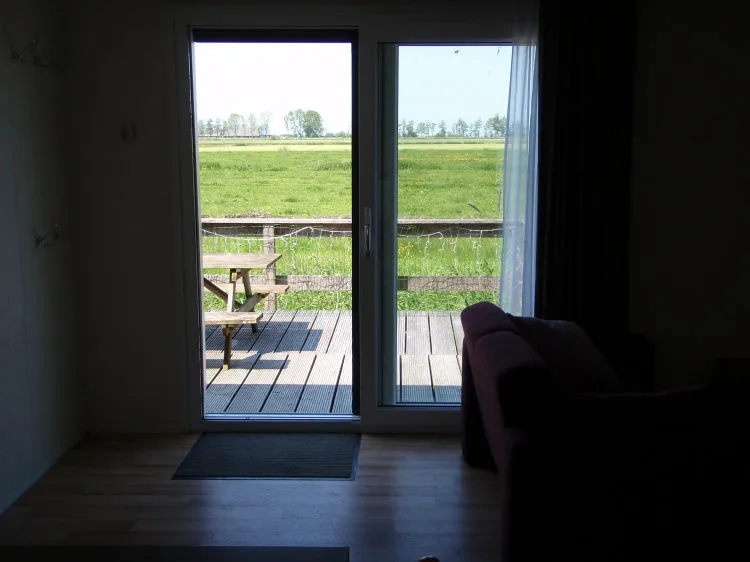 Doorkijkje vanuit het chalet naar het terras en weiland