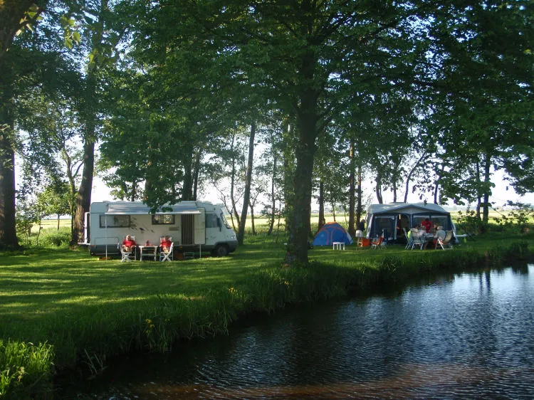 Camper en tent aan de slootkant in avondlicht