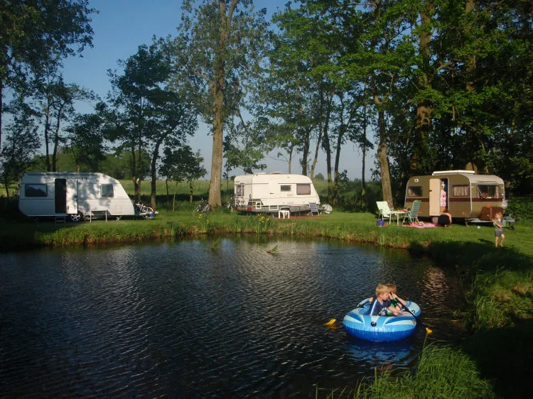 Caravans aan het water, kinderen in een rubberbootje